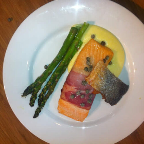 King Salmon Wrapped in Prosciutto with Asparagus, Crisp Capers, ‘Wafer of Skin’ on Soft Polenta